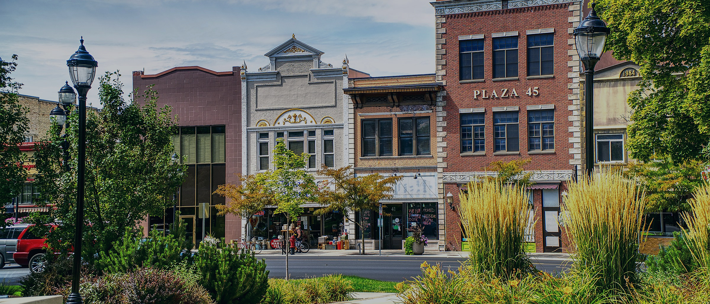 A small town main street lined with brick storefronts and shade trees