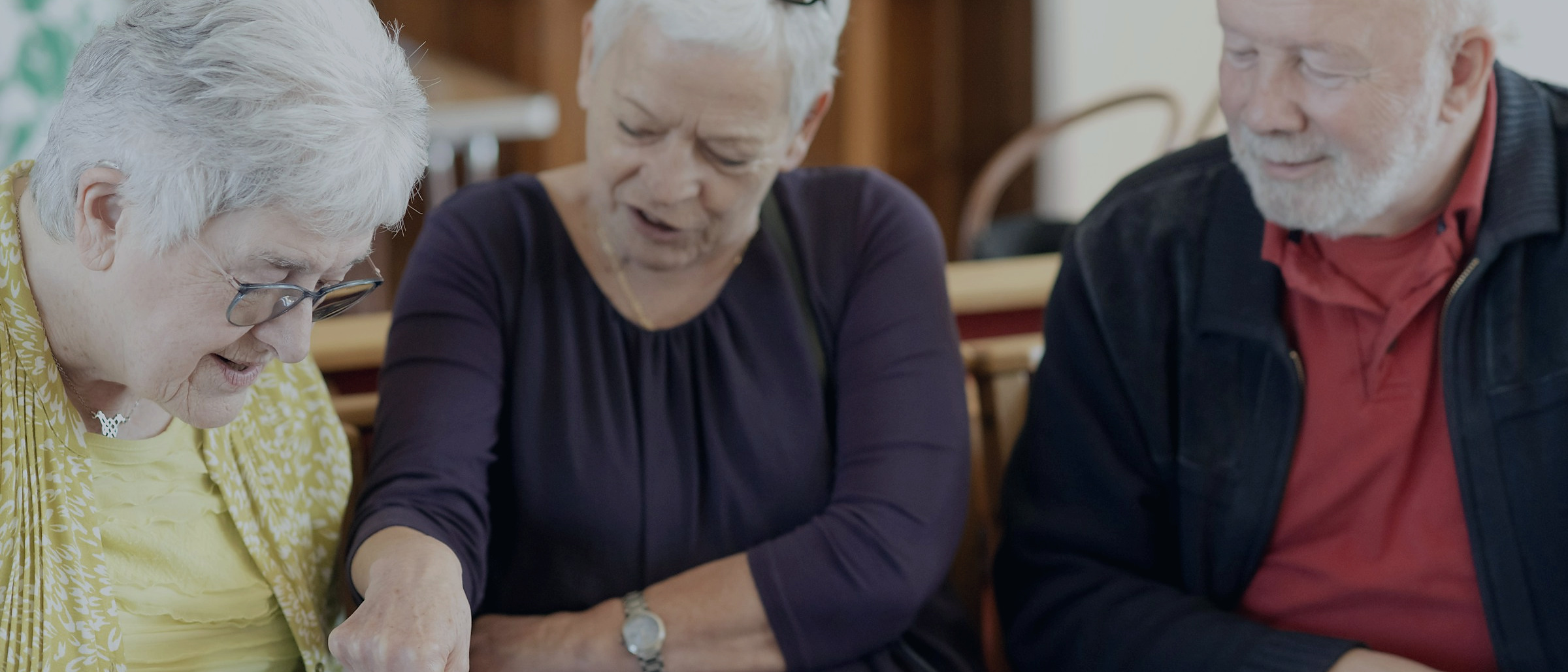 Three older adults reading through plan paperwork together at a table